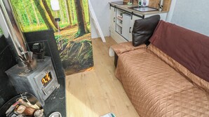 A compact room with a bed, a small kitchenette, a stove, and a large forest mural. - The Horse Box (Blaydon on Tyne)