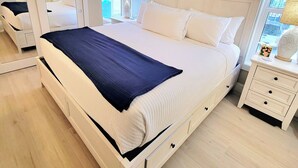 Hotellihuone, jossa on suuri sänky, yöpöytä, peili ja ikkuna, josta on näkymä.