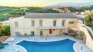 A building with a swimming pool, outdoor seating, and a view of mountains. - The Orestis Cottage House , Stalos, Crete (Chania)