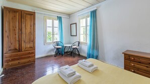 A room with a bed, wooden wardrobe, two chairs, a small table, and a window with curtains. - The Orestis Cottage House , Stalos, Crete (Chania)
