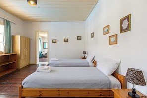 A bedroom with two beds, wooden furniture, a lamp, and framed pictures on the wall. - The Orestis Cottage House , Stalos, Crete (Chania)