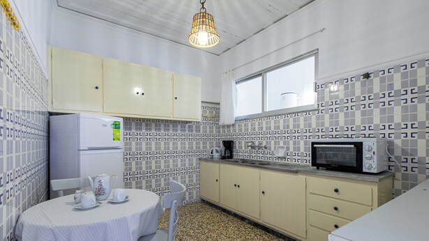 A kitchen with a refrigerator, microwave, and a table set with teacups. - The Orestis Cottage House , Stalos, Crete (Chania)