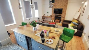 Une cuisine moderne avec un îlot central en bois, des armoires bleues et un tabouret de bar vert.