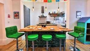 A kitchen with a central island, bar stools, and hanging light fixtures. - Church Retreat (St Leonards-On-Sea)