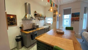A modern kitchen with a central island, a gas stove, and a stainless steel range hood. - Church Retreat (St Leonards-On-Sea)