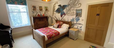 A bedroom with a wooden bed, a dresser, a nightstand, a window with a view, and a door.