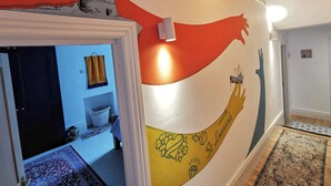 Un couloir orné d’une fresque murale, avec un luminaire et un tapis.