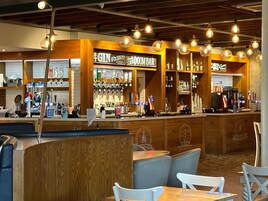 Una zona de bar con mostradores de madera, asientos y lámparas colgantes.