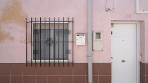 A pink building with a barred window, a white door, and a utility box. - Casita de San Juan in Cartagena, Murcia, Spain. (Cartagena)
