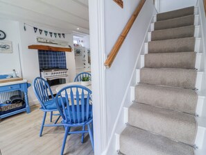 A staircase with beige carpeted steps and a wooden handrail. - Hideaway Cottage (Bideford)