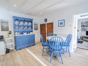 A dining area with blue chairs and a matching blue cabinet. - Hideaway Cottage (Bideford)