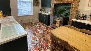 A kitchen with a patterned floor, a stove, and a brick wall. - 21 Gensing Road (St Leonards-On-Sea)