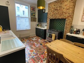 Une cuisine avec un carrelage décoratif, un fourneau et un mur en briques.