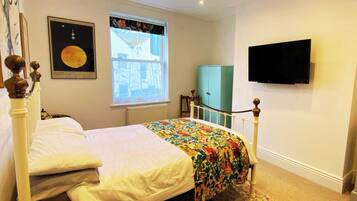 A bedroom with a bed, a window with a view, a television on the wall, and a cabinet.