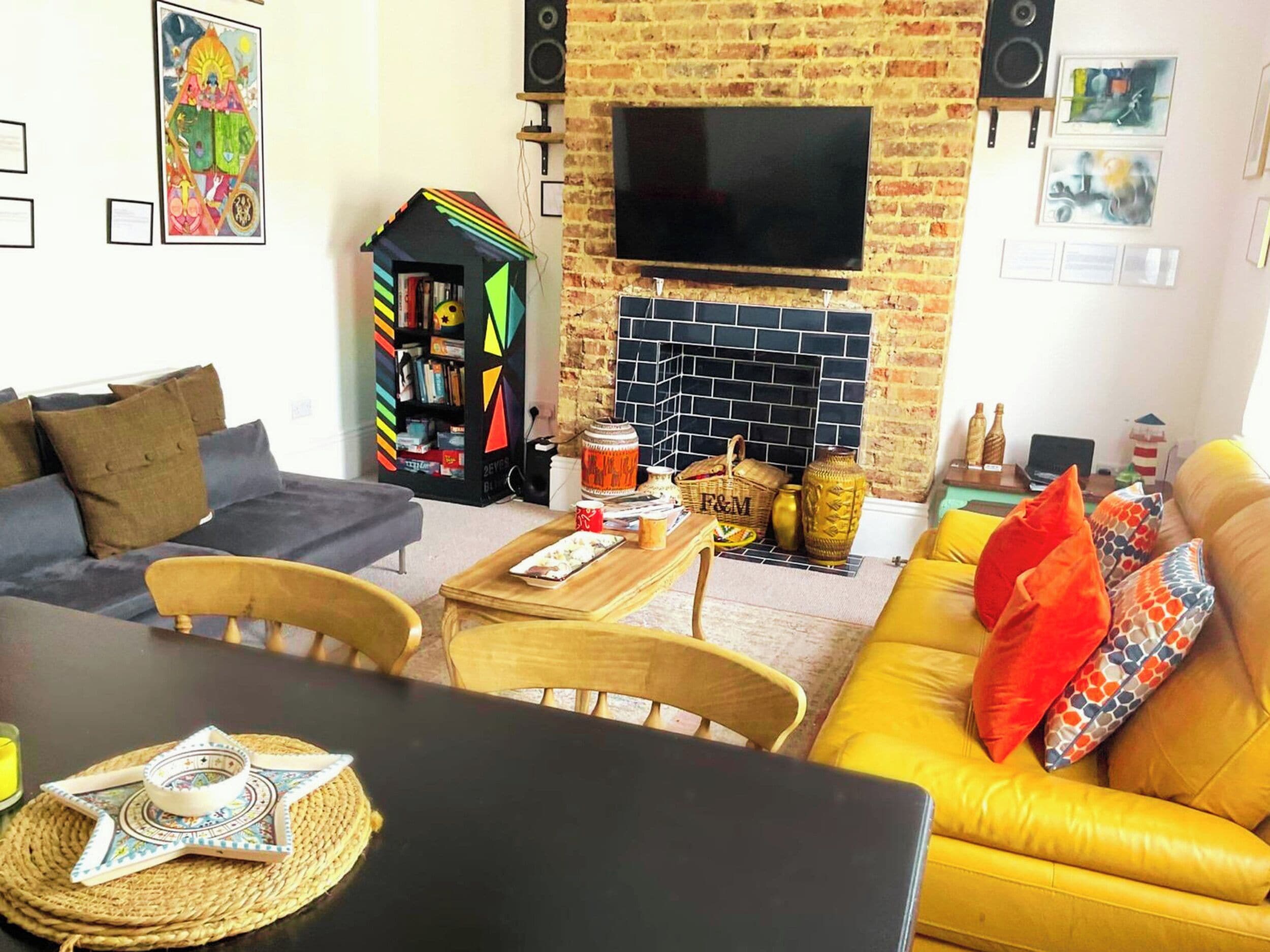 A living room with a sofa, a table, a bookshelf, a TV, and a fireplace.