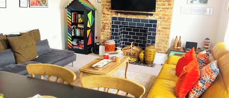 A living room with a sofa, a table, a bookshelf, a TV, and a fireplace.