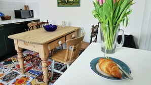 A dining table with a plate of croissant, a vase with flowers, and a blue bowl. - 21 Gensing Road (St Leonards-On-Sea)