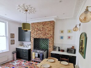 A kitchen with a brick wall, a stove, and a dining table set for four.