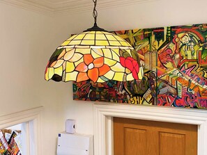 A room with a mosaic lamp, a colorful graffiti wall, and a white door. - 21 Gensing Road (St Leonards-On-Sea)