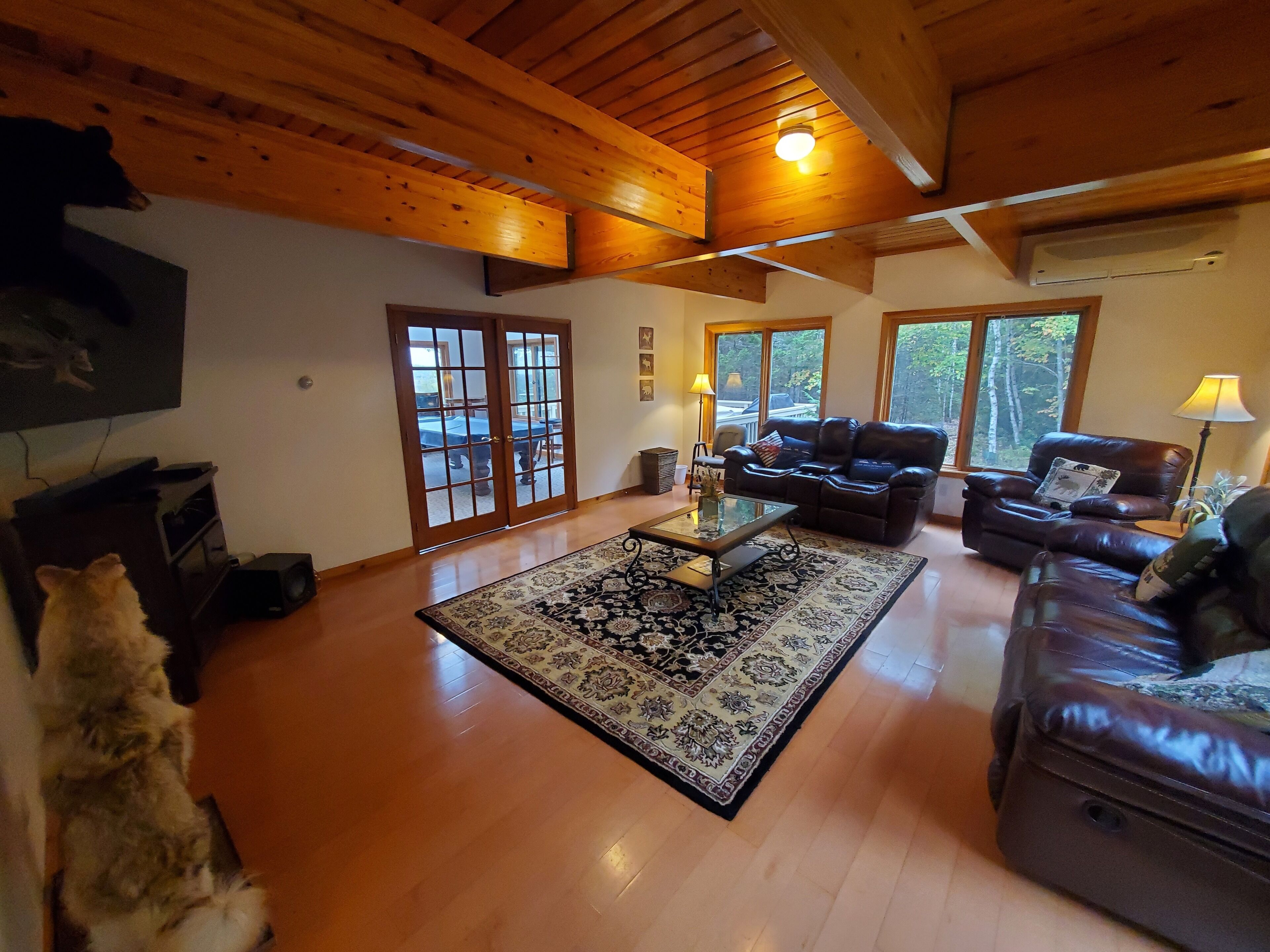 A spacious living room with wooden floors, a large sofa, a coffee table, and a television.