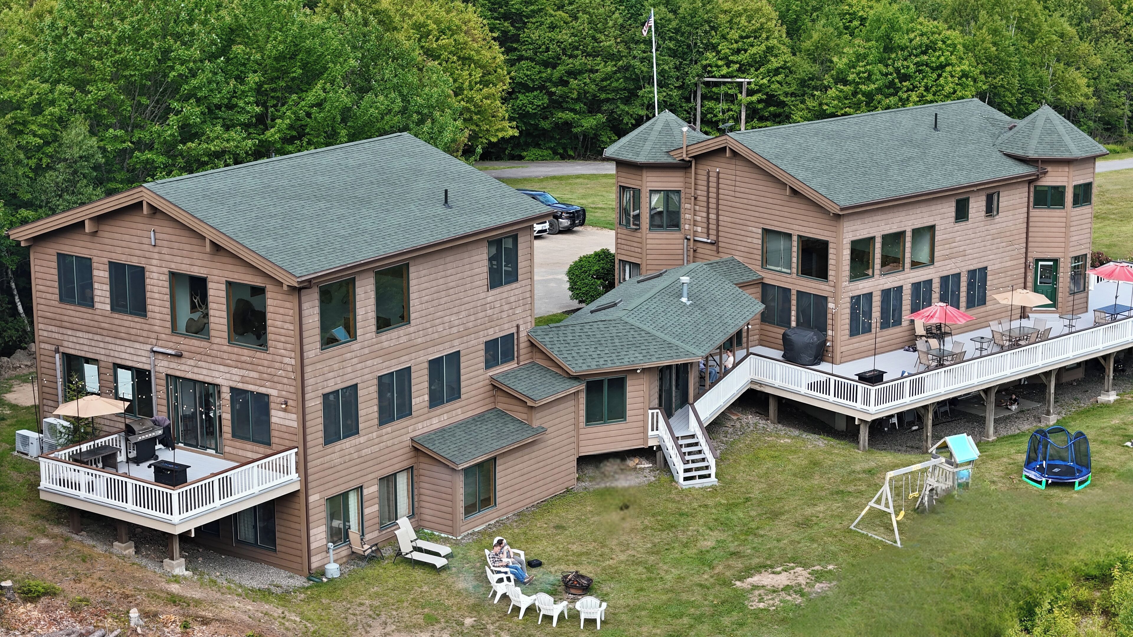 A large two-story building with a deck, outdoor seating, and a small play area.