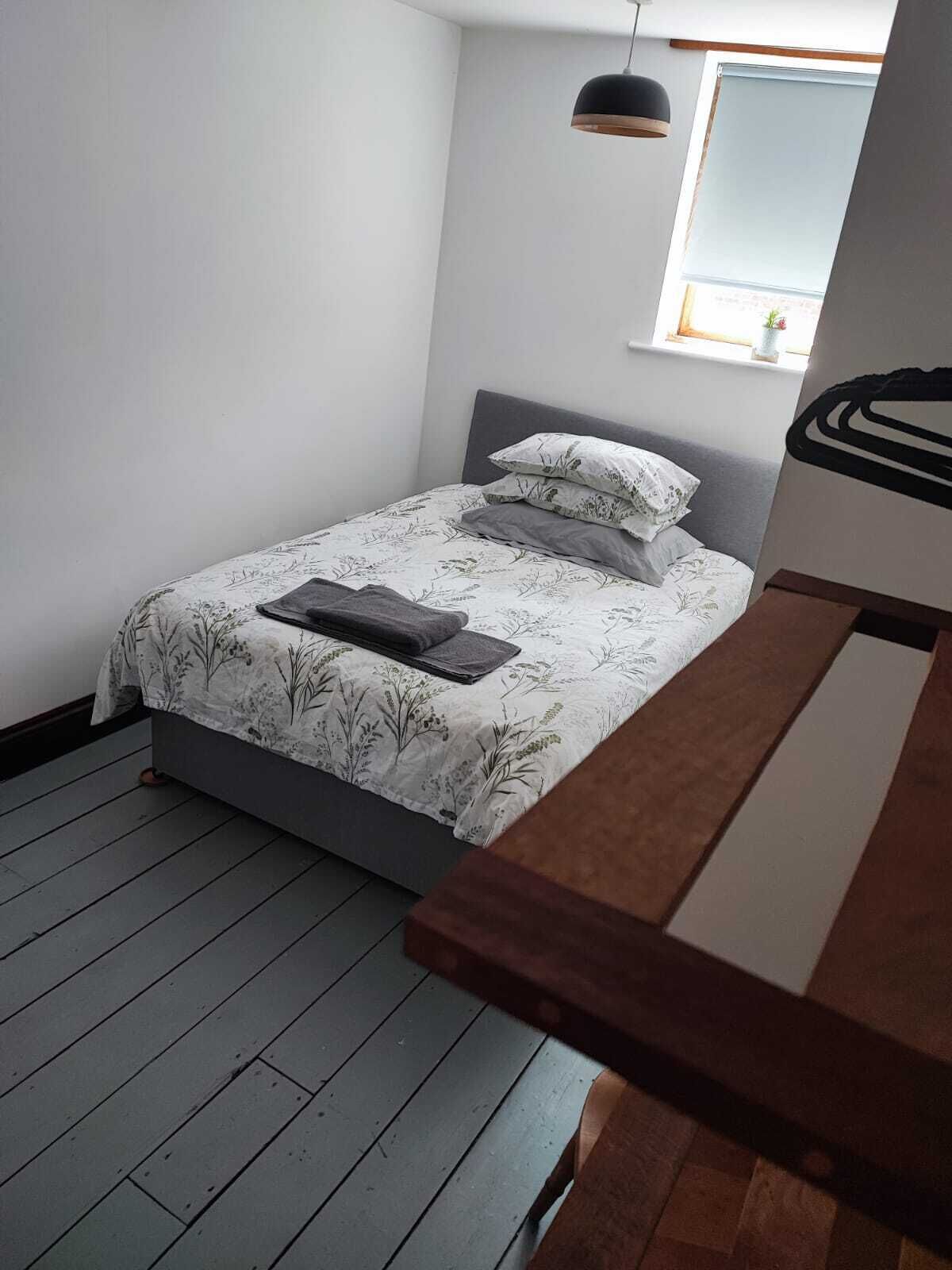 Une chambre à coucher avec un lit, une tête de lit grise, une fenêtre donnant sur un beau paysage et un luminaire suspendu.