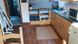 Pieni, käytännöllinen keittiö, jossa on puukaapit, mikroaaltouuni ja pesuallas.