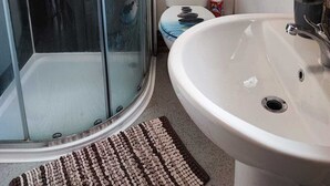 Kylpyhuone, jossa on lasiseinäinen suihkukaappi, wc ja pesuallas.