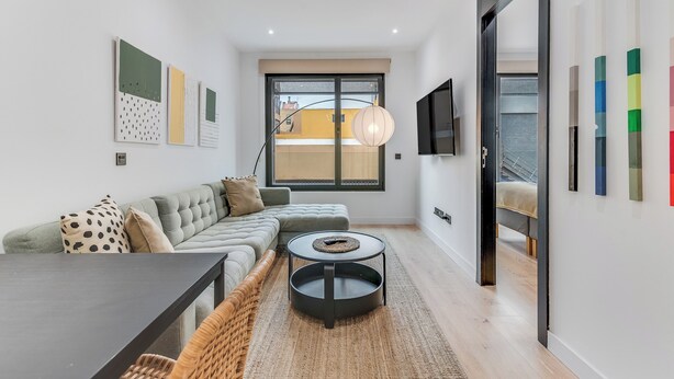 A modern living room with a sectional sofa, a round coffee table, a dining table, and a large window. - Home2Book Modern & Cozy Las Damas (Las Palmas de Gran Canaria)