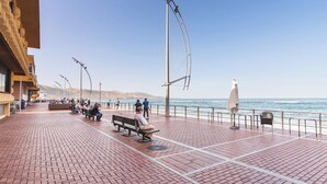 A paved promenade with benches and street lamps, overlooking a body of water. - Home2Book Modern & Cozy Las Damas (Las Palmas de Gran Canaria)