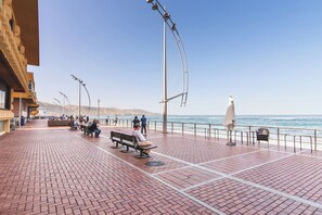 Eine gepflasterte Promenade mit Bänken und Laternen, mit Blick auf ein Gewässer.