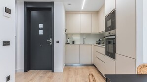 A modern kitchen with a black door, stainless steel appliances, and light-colored cabinets. - Home2Book Modern & Cozy Las Damas (Las Palmas de Gran Canaria)