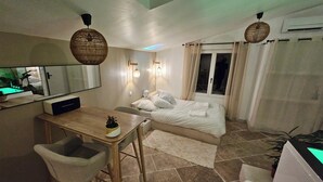 A bedroom with a bed, bedside table, chair, and a large mirror. - LA SUITE TILLEUIL (Montgé-en-Goële)