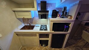 A compact kitchen with a sink, stove, microwave, and a coffee maker. - LA SUITE TILLEUIL (Montgé-en-Goële)