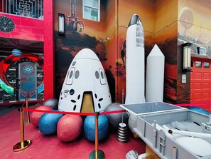 A space-themed exhibit with a rocket, spherical objects, and a solar panel. - Mission to Mars (Davenport)