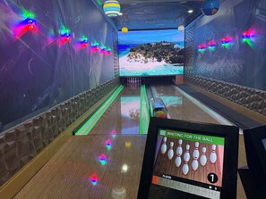 A bowling alley with a digital scoreboard, neon lights, and a mural of a snowy landscape. - Mission to Mars (Davenport)
