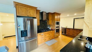 A modern kitchen with wooden cabinets, stainless steel appliances, and a black countertop.