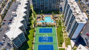 A high-rise hotel with multiple floors, a swimming pool, and tennis courts. - Serene Oceanview Haven Designer Coastal Living (South Padre Island)