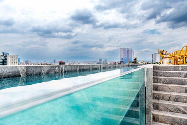 A rooftop pool with a city skyline in the background. - OH | Amazing 1BR Roma Nte w/ balcony, AC & Rooftop (Mexico City)