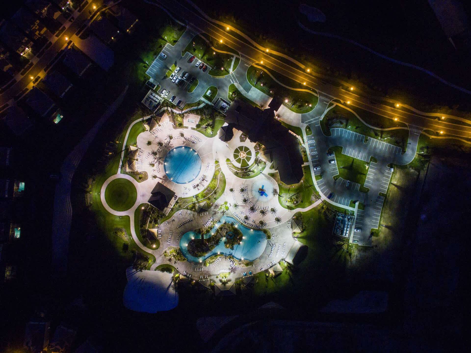An aerial view of a resort with multiple swimming pools, landscaped areas, and parking facilities.