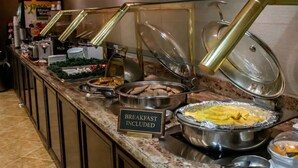 Un banco buffet con diversi cibi, incluso un cartello che indica la colazione inclusa.