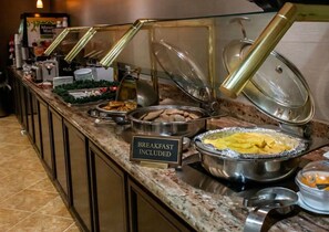 A buffet counter with various food items, including a sign indicating breakfast is included.