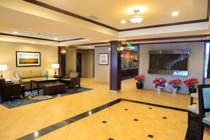 A lobby with a sofa, chairs, a coffee table, a reception desk, and potted plants.