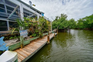 Una propiedad frente al agua con un muelle de madera, abundante vegetación y un letrero que indica 'Island Realty'.