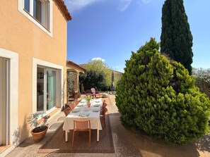 A patio with a table set for dining, surrounded by potted plants and a tall tree. - Villa Romarin - Family home in the heart of the southern Mediterranean (Narbonne)