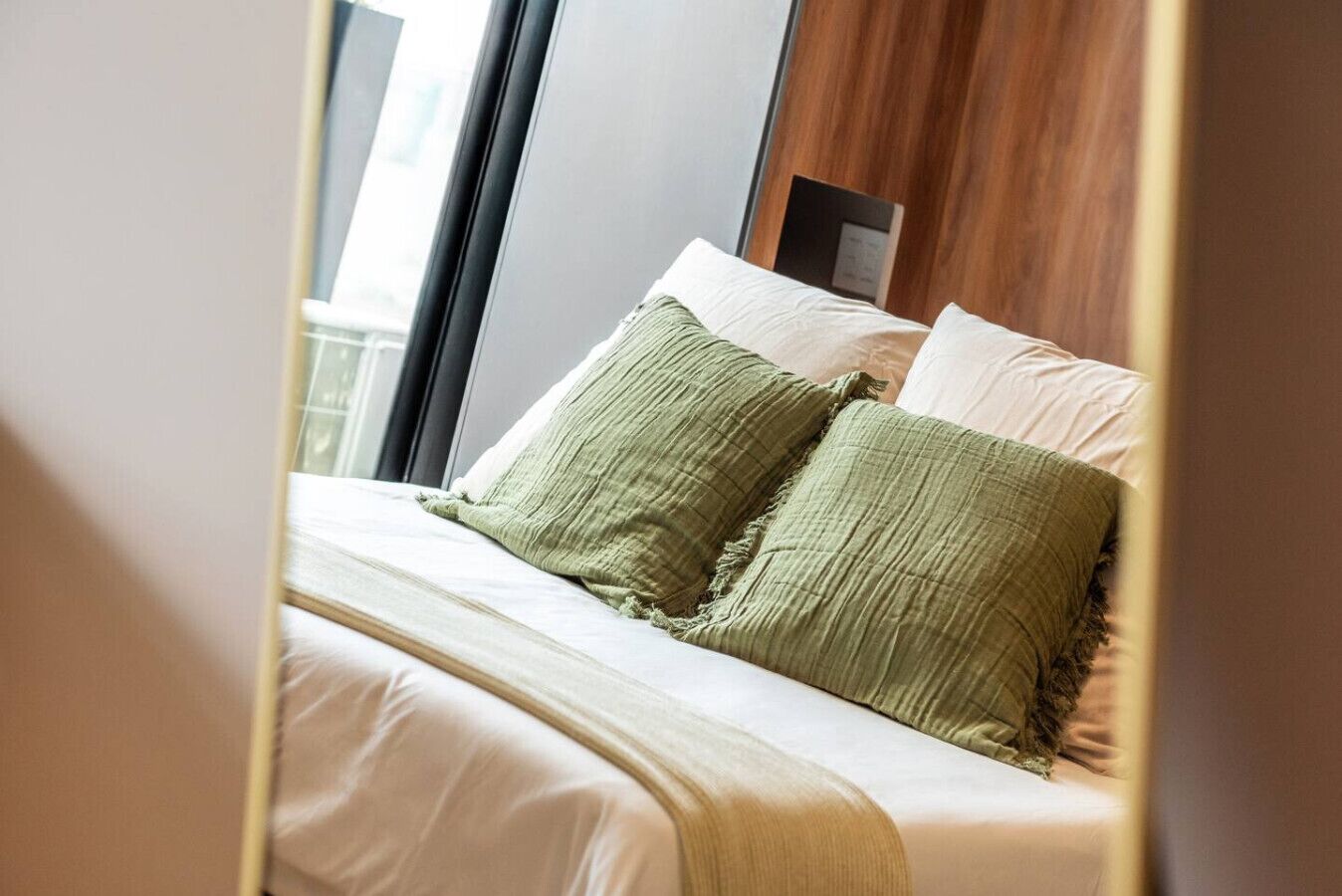 A hotel room with a bed, pillows, and a wooden headboard.