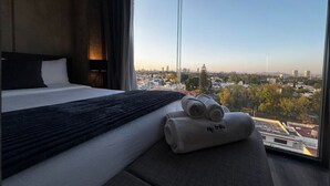 A hotel room with a large bed, a view of the city, and a window. - Amazing Suite consulado (Guadalajara)