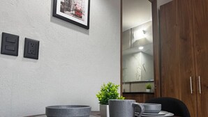 A dining table with plates, bowls, and a mug, a small potted plant, and a framed picture on the wall. - Amazing Suite consulado (Guadalajara)
