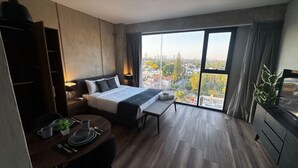 A modern hotel room with a large bed, a dining table, and a view of the city. - Amazing Suite consulado (Guadalajara)