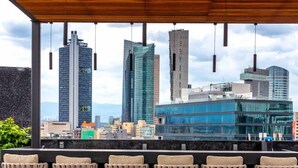 A covered outdoor bar area with a city skyline view, featuring modern buildings and a clear sky. - OH | Amazing Loft Roma Nte w/ AC (Mexico City)